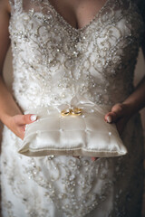 the bride holds a pillow with wedding rings