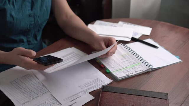 A woman calculating income and expenses. Family budget. Monthly payments. Paper list of monthly income and expenses close up. Financial crisis during Covid-19