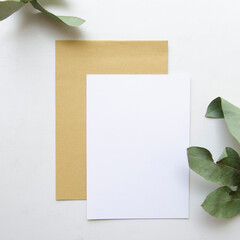 Vertical greeting card, postcard, invitation with envelope mock up on white background. Flat lay with eucalyptus.
