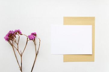 Horizontal greeting card, postcard, invitation with envelope mock up on white background. Flat lay with flower.