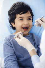 Little arab boy sitting at dental chair with open mouth during oral checking up with dentist doctor. Stomatology concept