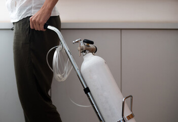 Woman is holding portable oxygen gas cylinder for use at home. Breathing device for asthma and...