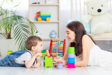 Fototapeta premium mom and baby boy play at home with educational toys in the children's room. A happy, loving family.