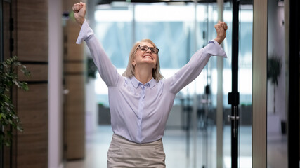 Overjoyed Caucasian middle-aged female employee feel euphoric celebrate work success in office....