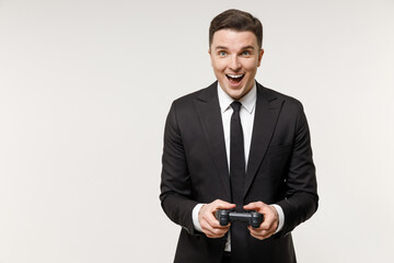 Naklejka premium Young overjoyed rich employee business corporate lawyer man in classic formal black grey suit shirt tie work in office play pc game with joystick console isolated on white background studio portrait.