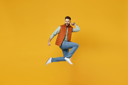 Full Length Side View Young Overjoyed Happy Fun Caucasian Man 20s Years Old Wearing Orange Vest Mint Sweatshirt Jump High Do Winner Gesture Clench Fist Isolated On Yellow Background Studio Portrait