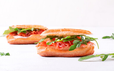 Eclair with salted trout, cream cheese and arugula on the white table