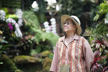 asian old elderly elder woman resting relaxing in rose garden. senior leisure lifestyle