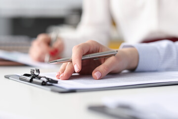 Hands of employees with documents and pens at work table