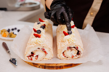 The process of making a meringue roll. A pastry chef decorates a meringue roll. Cooking meringue roll in the kitchen. Meringue roll with strawberries and grated chocolate.