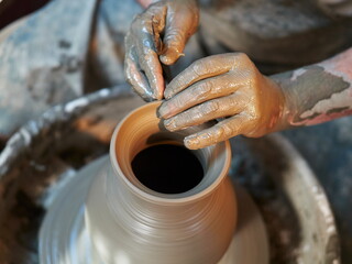 Potters hands are creating earthenware on potters wheel. Concept of natural materials, hand made and creativity