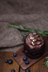 Gluten free cake with blueberry and carob. Homemade chocolate cake with berries and rosemary on brown wooden background with burlap cloth with copy space. Cacao sponge cake.