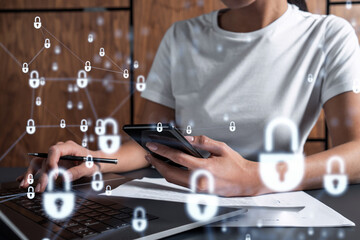 A woman programmer is typing a code on computer to protect a cyber security from hacker attacks and save clients confidential data. Padlock Hologram icons over the typing hands. Casual wear.