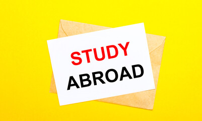 On a yellow background, an envelope and a card with the text STUDY ABROAD. View from above