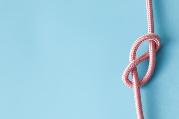 Blue background picture with a pastel pink rope. A concept for tying the knot, marriage and wedding
