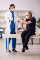 Obraz premium Old man visiting young doctor in covid-19 vaccination concept
