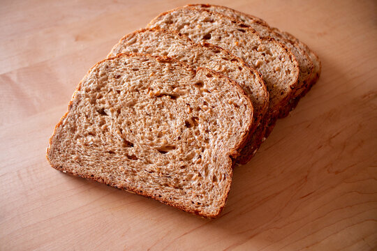 Several Slices Of Fresh Baked Whole Wheat Multi Grain Seeds Organic Bread On A Wood Block Kitchen Table