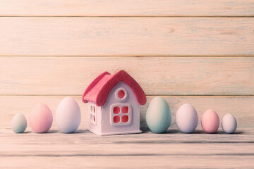 Obraz na płótnie Canvas House and painted Easter eggs over light wooden background