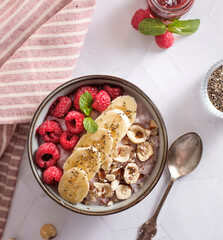 porridge with raspberries banana and nuts on coconut milk