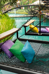 Comfortable colorful pillows lay on rope netting in garden for resting and relaxation..