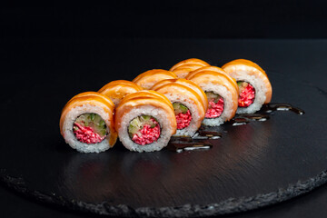 japanese food, rolls with tuna, unagi sauce and surimi filling on black background