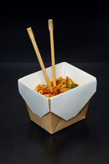 japanese food, wok udon noodles with meat and vegetables in an open box isolated on a solid background.