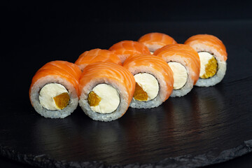 japanese food, rolls with salmon, philadelphia curd cheese and orange on black background