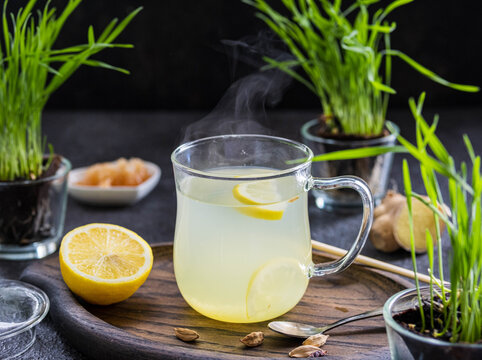 Ginger tea with lemon in a glass mug on a dark concrete background.