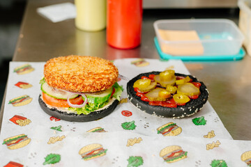 The process of making a chicken burger with fries in a black bun. The chef prepares a chicken burger with fries. Cooking burgers in the diner kitchen.