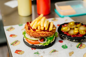 The process of making a chicken burger with fries in a black bun. The chef prepares a chicken burger with fries. Cooking burgers in the diner kitchen.