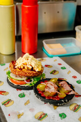 The process of making a chicken burger with fries in a black bun. The chef prepares a chicken burger with fries. Cooking burgers in the diner kitchen.