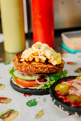 The process of making a chicken burger with fries in a black bun. The chef prepares a chicken burger with fries. Cooking burgers in the diner kitchen.
