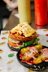 The process of making a chicken burger with fries in a black bun. The chef prepares a chicken burger with fries. Cooking burgers in the diner kitchen.