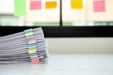 Piles of white papers work large piles of papers stacked together. On the desk in the office with colorful clip. Documents that are not finished in the office. Business concept.