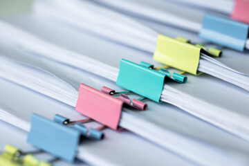 Fototapeta premium Piles of white papers work large piles of papers stacked together. On the desk in the office with colorful clip. Documents that are not finished in the office. Business concept.