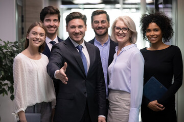 Smiling male CEO or director pose with office team stretch hand get acquainted greet with new...