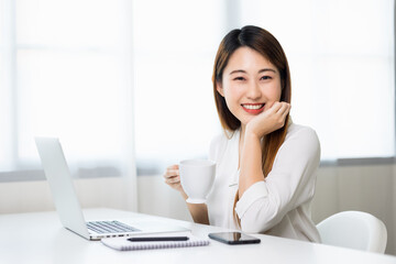 Young asian beautiful business woman working with laptop sitting at home drinking coffee. Smiling charming happy young female doing homework meeting conference with team at home.