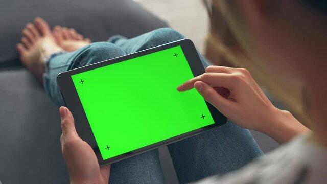 Close up of woman holding in hands a digital tablet with green screen for internet online, chroma key screen for advertising.