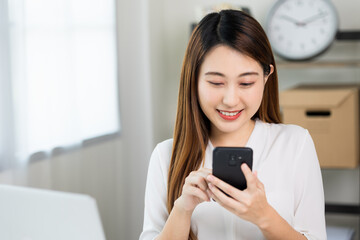 Fototapeta na wymiar Young asian beautiful business woman using smartphone. Smiling charming happy young female texting touching on display of cell phone.