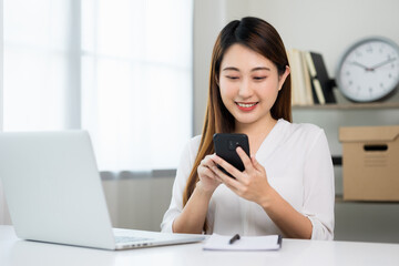 Young asian beautiful business woman using smartphone. Smiling charming happy young female texting touching on display of cell phone.