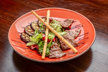 Pork meat grilled with fresh vegetable salad on a white plate.