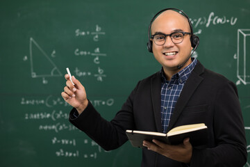 Young asian teacher man teaching video conference with student. Male Indian teacher training the mathematics in classroom from online course. He wearing small talk headset.