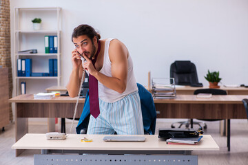 Young male employee coming to work straight from bed