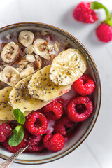 porridge with raspberries banana and nuts on coconut milk