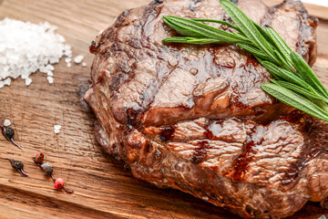grilled beef steaks with spices on wooden cutting board