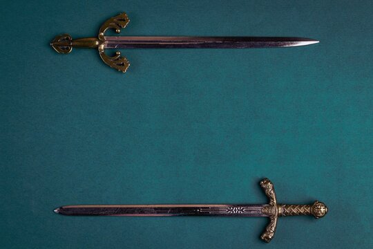 Two old knightly swords on a green velvet background. Copy space