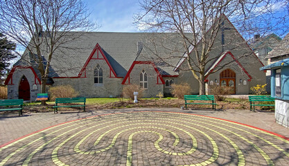 Old stone church with red trim - green park benches - a 7 layer labyrinth walk in the courtyard