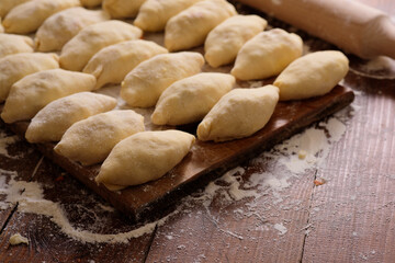 Raw homemade pies on a wooden background.