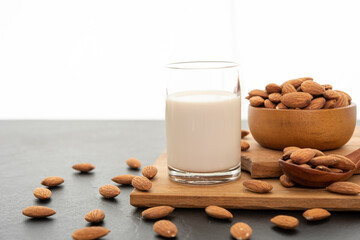 Almond milk with almond in a wooden spoon and bowl on a wooden (selective focus; close-up shot)