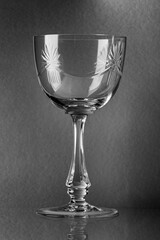 The glass is transparent, glass, under the wine, with patterns, on a gray background, with highlights